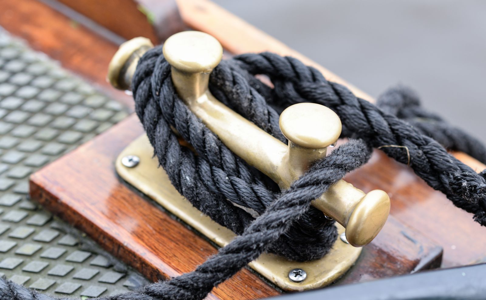 Brass cleat and line on varnished mahogany deck
